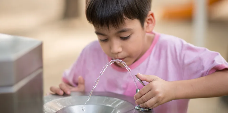 A photo of a child drinking water from a water fountain. Credit: Adobe Stock