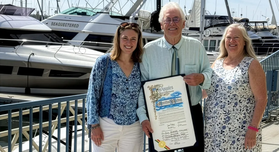 Photo of Jon Bishop holding a framed award standing with his wife and daughter. Credit: Jon Bishop